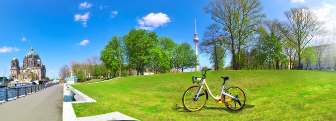 Riverside in Central Berlin with Cathedral on the left, bike on the green lawn and television tower...