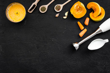 Cook orange cream soup with vegetables. Pumpkin, cream, spices, blender on black background top view copy space