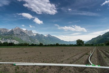 freshly plowed field with a clever irrigation system and a beautiful mountain landscape behind