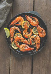 fried roasted shrimps in frying pan with lemon greens parsley garlic
