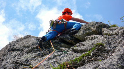 rock climber dressed in bright colors on a steep granite climbing route in the Alps