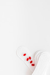 Women's hygiene products. Critical days concept. Sanitary pads and pills on white background top view copy space