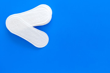 Women's hygiene products. Critical days concept. Sanitary pads on blue background top view copy space