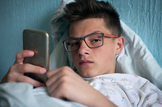 teenager lying in bed and using smartphone