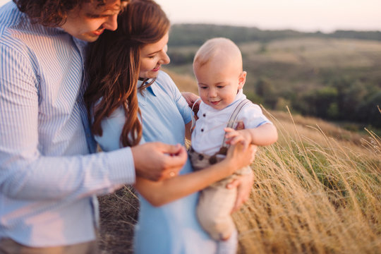 Young happy caucasian couple with baby boy. Parents and son having fun together. Mother and father play with toddler outdoors. Family, parenthood, childhood. Tilt-shift image, soft selective focus.