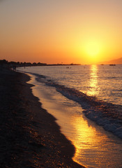 beautiful golden sunset reflected on the sea and wet beach sand in Kos Greece