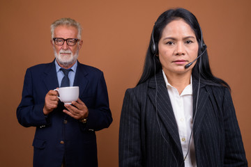 Mature multi-ethnic business couple against brown background