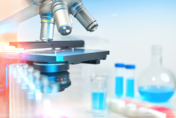Scientific background with closeup on light microscope and laboratory out of focus
