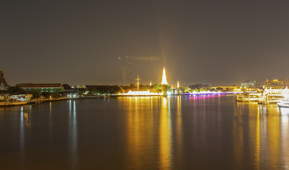 Obraz na płótnie Canvas View of Wat Arun at night, beautiful lights and water traffic.