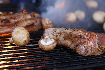 Meat and mushrooms are fried on the grill in a barbecue with flames. steak, champignons are fried over an open fire. Appetizing meal on the bbq. Grilled food. Picnic concept. Selective focus