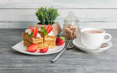 Honey cakes with strawberries and a cup of tea on a wooden background
