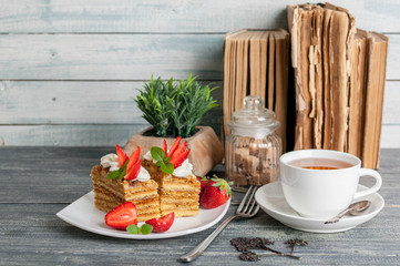 Honey cakes with strawberries and a cup of tea on a wooden background