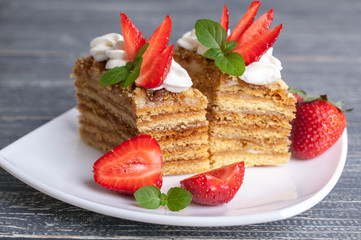 Honey cakes with strawberries and a cup of tea on a wooden background