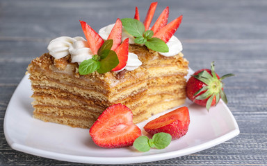Honey cakes with strawberries and a cup of tea on a wooden background