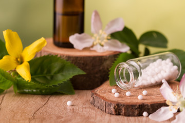 Bottle of homeopathic globules,homeopathic remedies and flowers