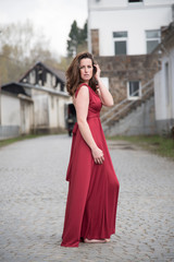 erotische junge Frau in langen roten Kleid auf altem Fabrikgelände