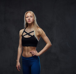 Sexy slim blonde girl in a sportswear posing in a studio.