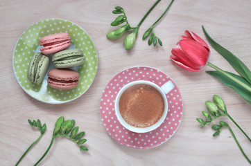 Macarons, espresso in pink cup, freesias and pink tulip, top view
