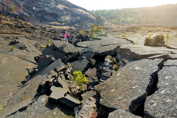 Young female tourist exploring surface of the Kilauea Iki volcano crater with crumbling lava rock in Volcanoes National Park in Big Island of Hawaii © MNStudio