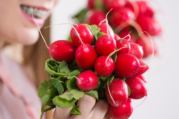 woman holding radish close to face