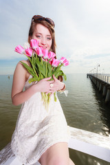 Woman holding bouquet of flowers sitting on pier