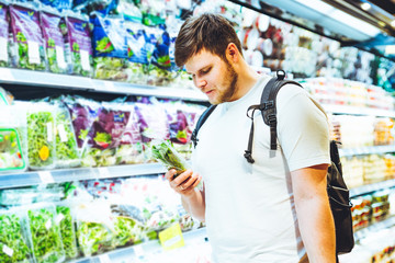 young smiling man choosing products in grocery store. shopping concept. lifestyle