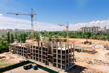 Fototapeta premium Building construction in city concept. View on cranes, building carcasses, concrete, sand and architectural materials