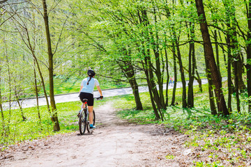 Obraz premium young woman ride bicycle in forest by trail