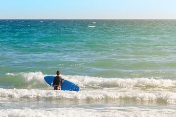 boy with surfboard standing in the water