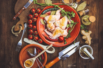 raw chicken wings and other food ingredients on a wooden background..