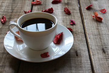 White coffee cup decorate with red dry rose on wood plate,vintage concept.