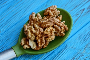 brown walnuts in a large green spoon