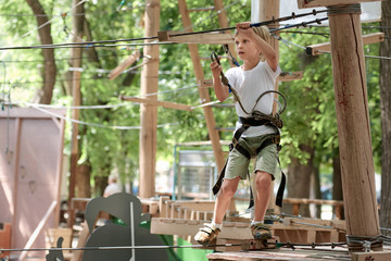 Portrait of little happy boy climbing in adventure park