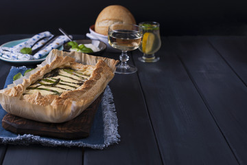 Open pie with asparagus and cheese, white wine and water. Vegetarian dinner. Healthy food. Homemade baking. Dark photo. Place for text. Horizontal photo
