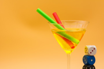 Horizontal View of Close up of a Tall Glass Yellow Cocktail with Three Colored Dices