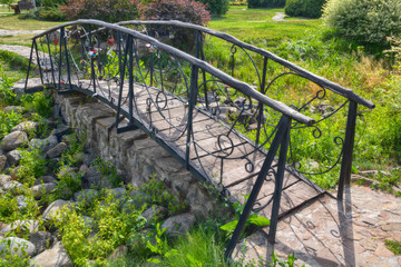 Beautiful metal forged bridge in a park consecrated by the sun. Bridge of Lovers