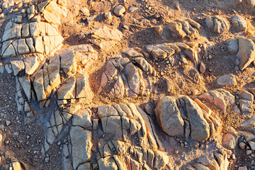 a close-up of cracked stones and sand on which sunlight shines