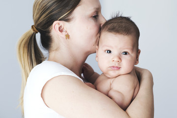 Young beautiful mother holding and kissing her newborn baby boy.  Love, cheerful, mother's care, happy family.