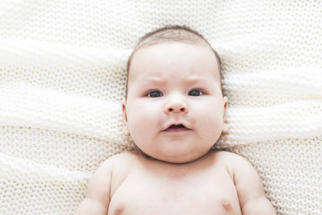 Newborn child relaxing in bed after bath or shower on white blanket. Happy and cheerful childhood.