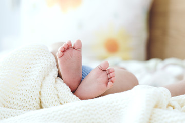 Close up of sleeping sweet baby boy legs in a bright bedroom covered with white blanket. Love, cheerful, mother's care.