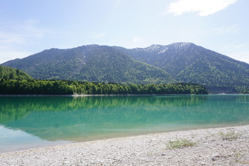 Very blue lake in the mountains of Bavaria in Germany with forrest