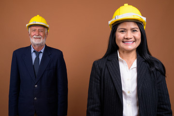 Mature multi-ethnic business couple against brown background