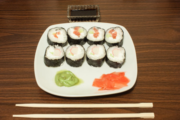 on a plate sliced sushi wasabi and pickled ginger, next sticks and soy sauce