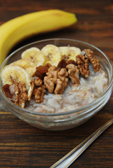 Top view of a Granola Bowl, Muesli with Oats, Nuts and Dried Fruit on Wooden table. Bannana, nuts, fruits. Healthy Breakfast. Diet.
