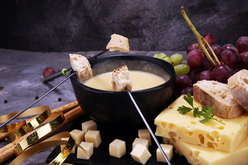Gourmet Swiss fondue dinner on a winter evening with assorted cheeses on a board alongside a heated pot of cheese fondue