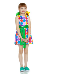 A little girl in a dress with a pattern from multi-colored circl