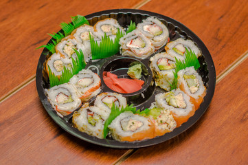 Large set of japanese sushi rolls on a black plastic plate