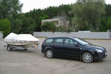 Tourism, transportation of water equipment - a car with a boat under a tent on a trailer on the...