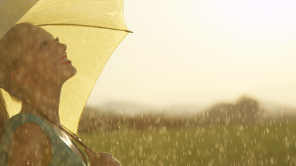 CLOSE UP: Happy young woman enjoys the fresh spring rain in a quiet green meadow