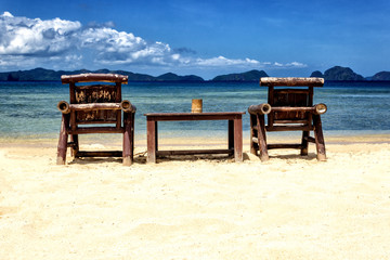 Table and chairs on an exotic beach on a hot sunny day against the blue sea and sky.